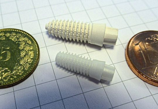 Spritzgegossener „Grünling“ und fertig gesintertes Kieferimplantat aus - Zirkoniumoxid. Das Teil besticht durch seine präzise konturierte Außenstruktur, die das Einwachsen in den Knochen begünstigt Spritzgegossener „Grünling“ und fertig gesintertes Kieferimplantat aus - Zirkoniumoxid. Das Teil besticht durch seine präzise konturierte Außenstruktur, die das Einwachsen in den Knochen begünstigt