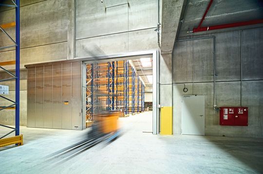 Im Tagesbetrieb gewähren Hörmann-Feuerschutz-Schiebetore die volle Durchgängigkeit. Im Brandfall schließen sie automatisch. Die daneben liegende Brandschutztür des Herstellers sichert den Fluchtweg.