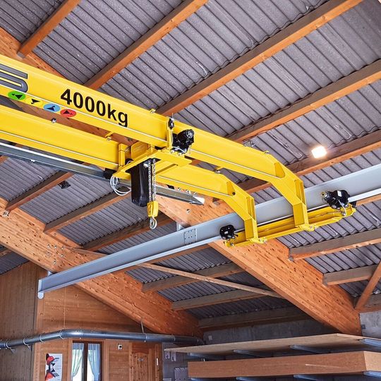 Zwischen den beiden an die Dachkonstruktion angepassten Kranträger ist der Elektrokettenzug vom Typ GCH2000, für eine Traglast von 4000 kg, an einem Joch in den Kran eingebaut. Zwischen den beiden an die Dachkonstruktion angepassten Kranträger ist der Elektrokettenzug vom Typ GCH2000, für eine Traglast von 4000 kg, an einem Joch in den Kran eingebaut.