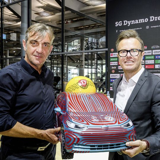 Dynamo Dresdens Sport-Geschäftsführer Ralf Minge (links) und Henning Schulzki, Vertriebs- und Marketingchef der Gläsernen Manufaktur, mit einem Miniaturmodell des VW ID 3.