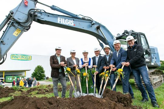 Gemeinsamer Spatenstich, im Hintergrund das bestehende Logistikzentrum von Rapunzel Naturkost im bayerischen Bad Grönenbach.