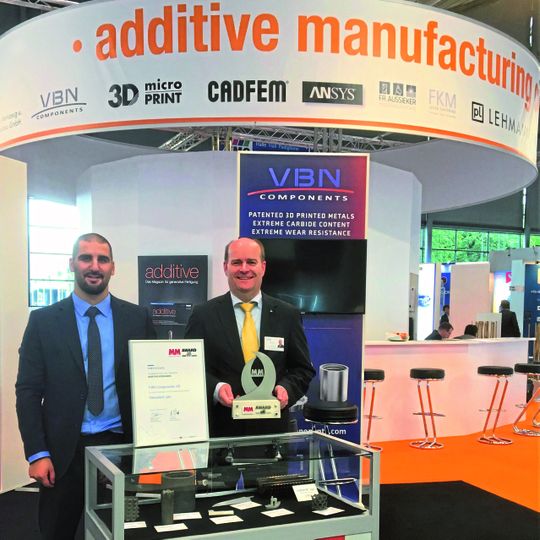CEO Martin Nilsson (r) and Process Engineer, Kristoffer Cederferm, at the company booth at EMO, proudly presenting the innovation award VBN won in additive manufacturing. CEO Martin Nilsson (r) and Process Engineer, Kristoffer Cederferm, at the company booth at EMO, proudly presenting the innovation award VBN won in additive manufacturing.