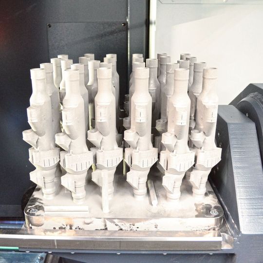 Auf der Spannvorrichtung der Bandsäge befestigte Grundplatte mit additiv gefertigten Werkstücken Auf der Spannvorrichtung der Bandsäge befestigte Grundplatte mit additiv gefertigten Werkstücken