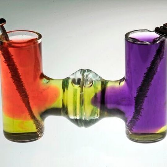 In a demonstration of the basic chemical reactions used in the new process, electrolysis takes place in neutral water. Dyes show how acid (pink) and base (purple) are produced at the positive and negative electrodes. In a demonstration of the basic chemical reactions used in the new process, electrolysis takes place in neutral water. Dyes show how acid (pink) and base (purple) are produced at the positive and negative electrodes.