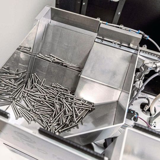 Die Schrauben werden über bewegliche Förderplatten vom Bevorratungsbehälter geräuscharm zur Zuführschiene bewegt. Die Schrauben werden über bewegliche Förderplatten vom Bevorratungsbehälter geräuscharm zur Zuführschiene bewegt.