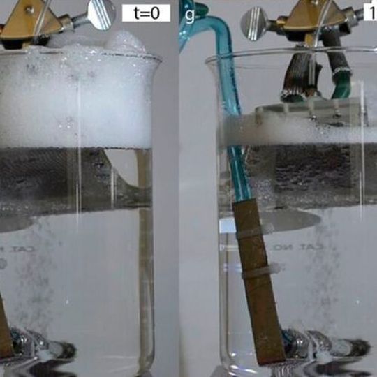 In a beaker with a constant stream of bubbles, a piece of the new textured material developed by the MIT team is inserted which causes the foam buildup at the top of the beaker to dissipate almost completely within ten minutes. In a beaker with a constant stream of bubbles, a piece of the new textured material developed by the MIT team is inserted which causes the foam buildup at the top of the beaker to dissipate almost completely within ten minutes.