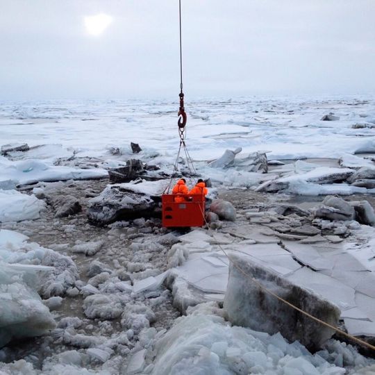 This image shows sediment-rich sea ice in the Transpolar Drift Stream. A crane lowers two researchers from the decks of the icebreaker RV Polarstern to the surface of the ice to collect samples. This image shows sediment-rich sea ice in the Transpolar Drift Stream. A crane lowers two researchers from the decks of the icebreaker RV Polarstern to the surface of the ice to collect samples.
