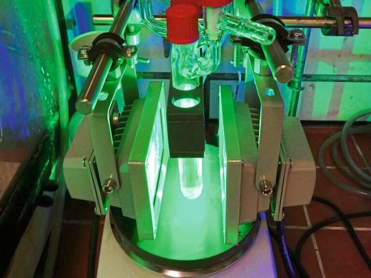 Kolben mit dem Titan-Katalysator und dem roten Farbstoff, die im Labor des Kekulé-Instituts für Organische Chemie und Biochemie der Universität Bonn mit grünem Licht bestrahlt werden. Kolben mit dem Titan-Katalysator und dem roten Farbstoff, die im Labor des Kekulé-Instituts für Organische Chemie und Biochemie der Universität Bonn mit grünem Licht bestrahlt werden.