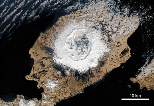 Satellitenbildaufnahme der Insel Umnak in der Kette der Aleuten-Inseln, die zum Pazifischen Feuerring gehören. Auf der Insel erhebt sich Okmok als breiter Schildvulkan 1073 Meter über dem Meeresspiegel mit einer 10 Kilometer breiten Caldera, die während des Ausbruchs im Jahr im Jahr 43 vor Christus geformt wurde. Satellitenbildaufnahme der Insel Umnak in der Kette der Aleuten-Inseln, die zum Pazifischen Feuerring gehören. Auf der Insel erhebt sich Okmok als breiter Schildvulkan 1073 Meter über dem Meeresspiegel mit einer 10 Kilometer breiten Caldera, die während des Ausbruchs im Jahr im Jahr 43 vor Christus geformt wurde.