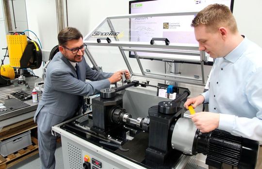 Prof. Udo Jung (links) und Doktorand Andreas Kern bereiten eine Umlaufbiegeprüfmaschine für den Test einer Werkstoffprobe vor.