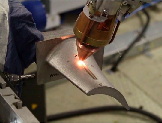 Bild 1: Blick auf den Turbinenschaufeldemonstrator, durch den zwei unterschiedliche additive Fertigungsverfahren beweisen, dass man solche Bauteile noch einfacher und wirksamer mit Sensoren funktionalisieren kann. Hier sieht man das Laserauftragschweißen. Bild 1: Blick auf den Turbinenschaufeldemonstrator, durch den zwei unterschiedliche additive Fertigungsverfahren beweisen, dass man solche Bauteile noch einfacher und wirksamer mit Sensoren funktionalisieren kann. Hier sieht man das Laserauftragschweißen.