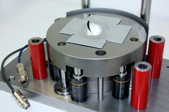 In der Prüfmaschine drückt ein halbkugelförmiger Stempel das Werkstück bis zu einer definierten Tiefe ein. Die Analyse des Kraft-Weg-Verlaufs erlaubt detaillierte Rückschlüsse auf die Qualität des Materials. In der Prüfmaschine drückt ein halbkugelförmiger Stempel das Werkstück bis zu einer definierten Tiefe ein. Die Analyse des Kraft-Weg-Verlaufs erlaubt detaillierte Rückschlüsse auf die Qualität des Materials.
