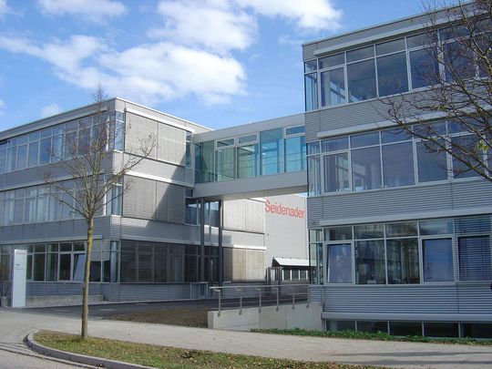 Eine gläserne Brücke auf Höhe des oberen Geschosses verbindet den Neubau der Seidenader-Gruppe mit dem Altbau und schafft so eine Einheit. Bild: Seidenader Eine gläserne Brücke auf Höhe des oberen Geschosses verbindet den Neubau der Seidenader-Gruppe mit dem Altbau und schafft so eine Einheit. Bild: Seidenader