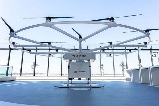 I fly emissionsfrei! Volocopter und DB Schenker präsentieren die Frachtdrohne namens Volodrone. Und zwar im Rahmen der Nationalen Luftfrachtkonferenz in Berlin. I fly emissionsfrei! Volocopter und DB Schenker präsentieren die Frachtdrohne namens Volodrone. Und zwar im Rahmen der Nationalen Luftfrachtkonferenz in Berlin.