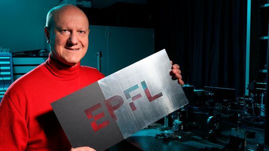 Des chercheurs de l'EPFL ont mis au point une nouvelle technique d'impression : enlever de la matière plutôt que d'en ajouter. Ici, Olivier Martin tient le logo de l'EPFL, réalisé avec cette méthode. Des chercheurs de l'EPFL ont mis au point une nouvelle technique d'impression : enlever de la matière plutôt que d'en ajouter. Ici, Olivier Martin tient le logo de l'EPFL, réalisé avec cette méthode.