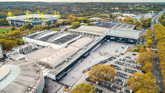 Drohnenaufnahme: Die Westfalenhallen Unternehmensgruppe zapft nachhaltig Strom aus Sonnenlicht auf den Dächern von vier Messehallen. Hinten links ist das Fußballstadion von Borussia Dortmund zu erkennen. Drohnenaufnahme: Die Westfalenhallen Unternehmensgruppe zapft nachhaltig Strom aus Sonnenlicht auf den Dächern von vier Messehallen. Hinten links ist das Fußballstadion von Borussia Dortmund zu erkennen.