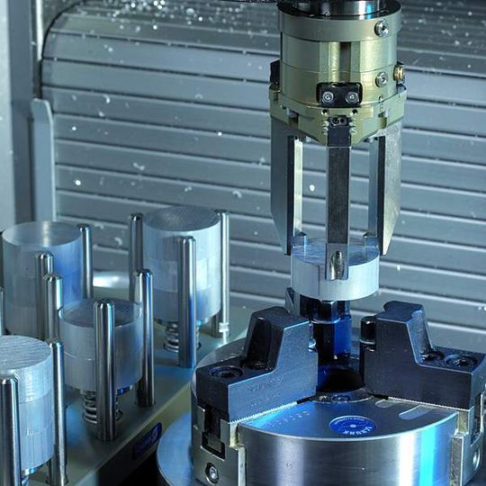 Bild 1: Wie ein Werkzeug wird der Spindelgreifer automatisch über die Achsen der Maschine verfahren. Aus dem Rohteilmagazin setzt der Greifer das Werkstück in das 3-Backen-Futter. Bild 1: Wie ein Werkzeug wird der Spindelgreifer automatisch über die Achsen der Maschine verfahren. Aus dem Rohteilmagazin setzt der Greifer das Werkstück in das 3-Backen-Futter.