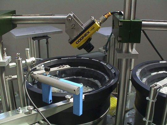 Kamera in erster Prüfstation: Die Filtergehäuse werden über den Rüttelförderer der Produktionslinie zugeführt. Die im autark arbeitenden Vision-System In-Sight 5100 integrierte Bildverarbeitungs-Software kontrolliert die Kunststoffteile im Auslauf des Rüttelförderers auf einwandfreie Ausrichtung und Drehlage. Nur Gutteile gehen in die weitere Produktion Kamera in erster Prüfstation: Die Filtergehäuse werden über den Rüttelförderer der Produktionslinie zugeführt. Die im autark arbeitenden Vision-System In-Sight 5100 integrierte Bildverarbeitungs-Software kontrolliert die Kunststoffteile im Auslauf des Rüttelförderers auf einwandfreie Ausrichtung und Drehlage. Nur Gutteile gehen in die weitere Produktion
