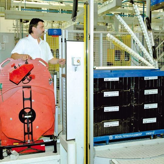 Das Verpackungsband wird mit der Kettenlanze unter dem Paket durch und auf der anderen Seite wieder hochgefahren. Dann kann der Bediener die Bandenden greifen, spannen und verschweißen.Bild: Audi Das Verpackungsband wird mit der Kettenlanze unter dem Paket durch und auf der anderen Seite wieder hochgefahren. Dann kann der Bediener die Bandenden greifen, spannen und verschweißen.Bild: Audi