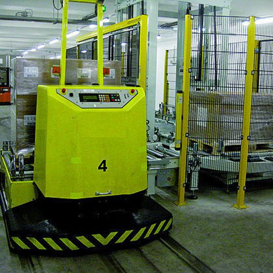 Bild 1: Am Übergabepunkt „Verpackung“ werden die Paletten vom fahrerlosen Transportsystem an einen Senkrechtförderer zum Transport zu den Verpackungsanlagen im Erdgeschoss übergeben. Bild: Siemens Bild 1: Am Übergabepunkt „Verpackung“ werden die Paletten vom fahrerlosen Transportsystem an einen Senkrechtförderer zum Transport zu den Verpackungsanlagen im Erdgeschoss übergeben. Bild: Siemens