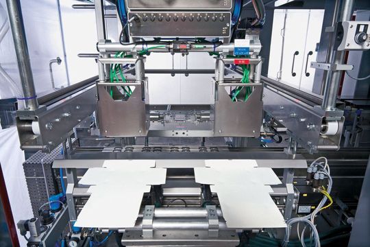 Einblick in das Innenleben der Aufrichtemaschine: Zu sehen sind Aufrichtestempel, die Leimdüsen mit ihren Stellmotoren (rechts unten) und das neue Faltwerkzeug im Hintergrund. (Bild: Bilder: Gerhard Schubert)