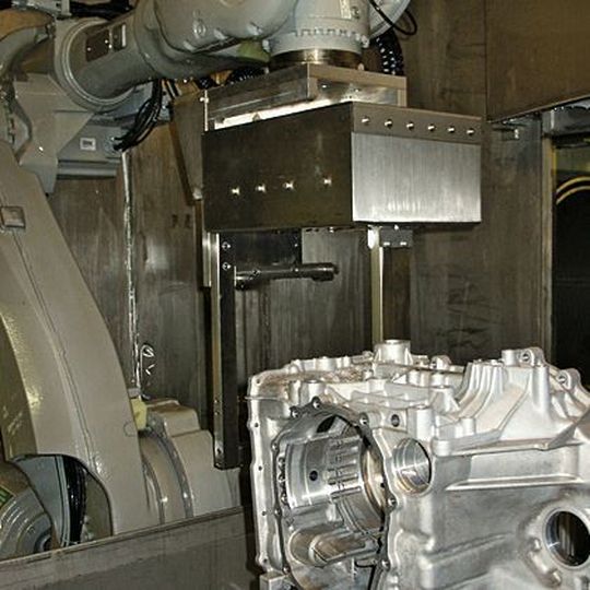 Bild 1: Zum Hochdruckentgraten nimmt der Roboter das Werkstück auf und führt es in der Entgratstation an einer Lanze entlang. Bild 1: Zum Hochdruckentgraten nimmt der Roboter das Werkstück auf und führt es in der Entgratstation an einer Lanze entlang.