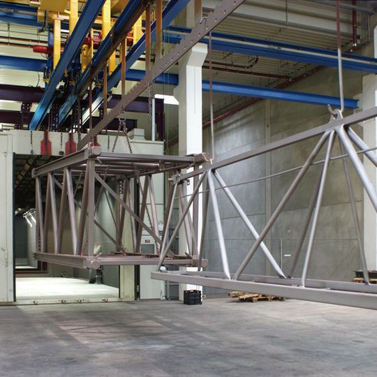 Bild 1: Vor der Pulverlackbeschichtung werden die Stahlkonstruktionen für Turmkrane gestrahlt. Für den Transport per Hängebahnsystem wurden schmale Aufnahmegestelle konzipiert. Bild: Wilbert/Agtos Bild 1: Vor der Pulverlackbeschichtung werden die Stahlkonstruktionen für Turmkrane gestrahlt. Für den Transport per Hängebahnsystem wurden schmale Aufnahmegestelle konzipiert. Bild: Wilbert/Agtos