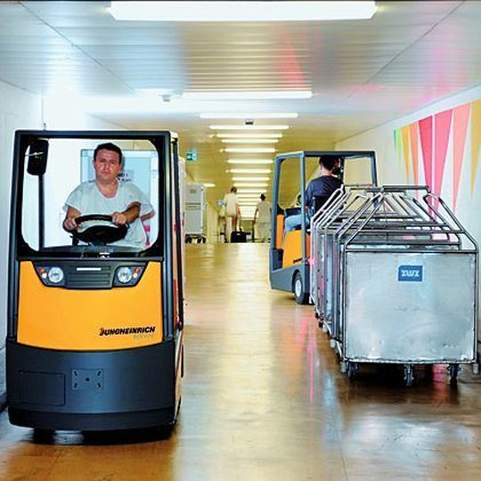 Bis zu fünf Wagen, mit Wäsche, Essen oder Apothekenartikeln beladen, zieht der Elektroschlepper EZS 570 von Jungheinrich im Universitätsspital Zürich mit seinen insgesamt rund 20 km langen unterirdischen Gängen. Bild: Jungheinrich Bis zu fünf Wagen, mit Wäsche, Essen oder Apothekenartikeln beladen, zieht der Elektroschlepper EZS 570 von Jungheinrich im Universitätsspital Zürich mit seinen insgesamt rund 20 km langen unterirdischen Gängen. Bild: Jungheinrich