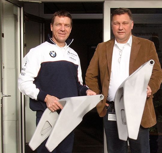 Pete Goddard, Entwicklungsingenieur bei alpha Racing (links) und Georg Borgschulte, Vertriebsleiter ZOLLERN Feinguss Soest (rechts) mit der neuen Hightech-Hinterradschwinge (Bild: Zollern)