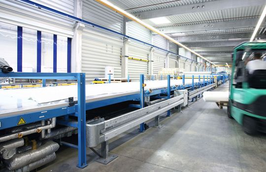 Auf mehren 100 m langen Produktionslinien werden CFK-Bahnen mit Oberflächenversiegelung für Fahrzeugaufbauten hergestellt. (Bild: Lamilux)