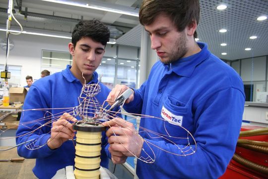 Die Ceramtec-Auszubildenden Aliekber Düzgün (links) und Steffen Benzing verbinden den vorderen Drahtkörper der "Wire-Bee" mit der Ziehwalze. (Bild: Ceramtec)