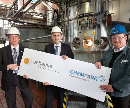 Chempark-Leiter Dr. Ernst Grigat, Axel Ebbecke, Geschäftsführer der Ebbecke Spraytech, und Ebbecke-Betriebsleiter Stefan Hagedorn vor einem Sprühtrockner im Werk des neu gegründeten Unternehmens. (Bild: Currenta)