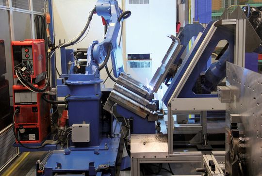 In der Schweißzelle hat ein Roboter die Vorrichtung ersetzt, er hält das Teil, während der Schweißroboter die Nähte zieht. In der Schweißzelle hat ein Roboter die Vorrichtung ersetzt, er hält das Teil, während der Schweißroboter die Nähte zieht.