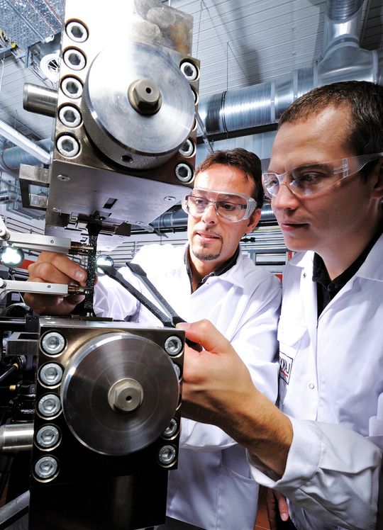 Markierte Probekörper werden für einen Zugversuch in eine Prüfmaschine eingespannt. Die genaue Kenntnis der Materialdaten ist bei der rechnerischen Auslegung von Hybridbauteilen aus Organoblech und angespritzten Funktionselementen unverzichtbar.