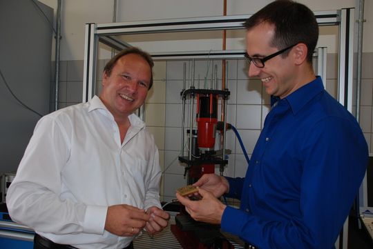 Der wissenschaftliche Mitarbeiter des Projekts, Dipl.-Ing. Philipp Skoda (rechts) zeigt Prof. Greitmann eingeschossene Nägel in Proben aus Kupfer.