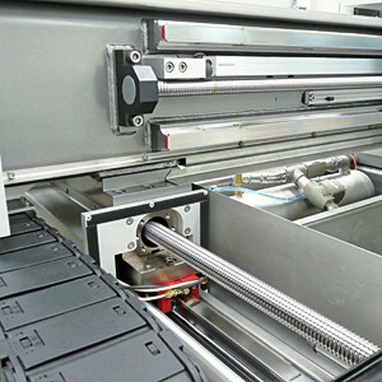 Die Microwaterjet-Maschinen verfügen über ein beidseitig gelagertes Portal, das über zwei Kugelrollspindeln angetrieben wird (im Bild). Für die Positioniergenauigkeit im Mikrometerbereich sorgen unter anderem Glasmaßstäbe über die volle Länge. Die Microwaterjet-Maschinen verfügen über ein beidseitig gelagertes Portal, das über zwei Kugelrollspindeln angetrieben wird (im Bild). Für die Positioniergenauigkeit im Mikrometerbereich sorgen unter anderem Glasmaßstäbe über die volle Länge.