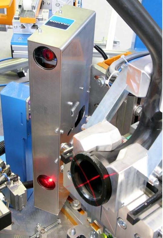 Detailansicht einer Laserprojektion auf den zu vermessenden Flansch und den danebenliegenden Sensorkopf der Gegenseite.