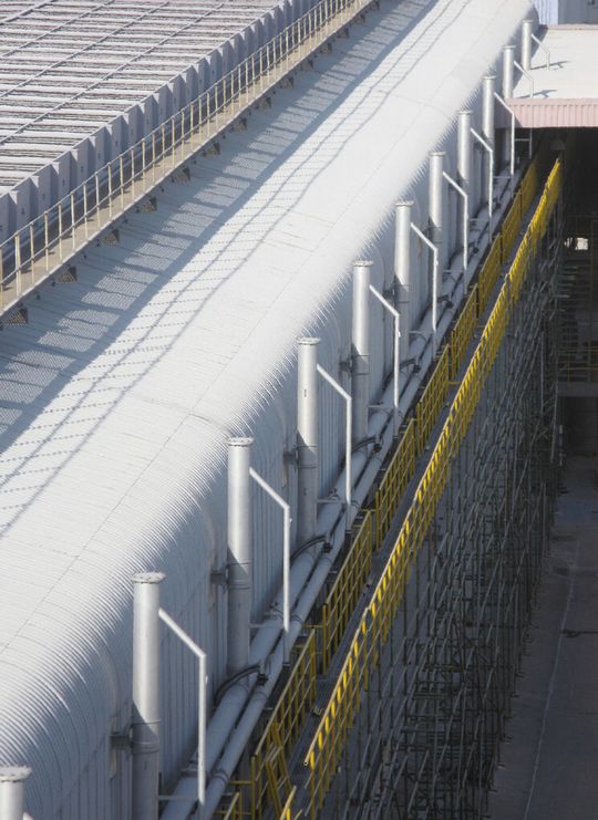 Außenansicht auf die Anlage mit 64 Elektrolysezellen, die mit dem pneumatischen Fördersystem Durodense zur automatischen Zellenbeschickung aufgerüstet wurden. Außenansicht auf die Anlage mit 64 Elektrolysezellen, die mit dem pneumatischen Fördersystem Durodense zur automatischen Zellenbeschickung aufgerüstet wurden.