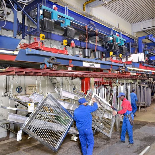 An Ringbahnen durchlaufen die feuerzuverzinkenden Teile die Bäder. Ausgangspunkt und Endpunkt sind die Aufgabe-/Abnahmestationen, an denen die Traversen abgesenkt werden. An Ringbahnen durchlaufen die feuerzuverzinkenden Teile die Bäder. Ausgangspunkt und Endpunkt sind die Aufgabe-/Abnahmestationen, an denen die Traversen abgesenkt werden.