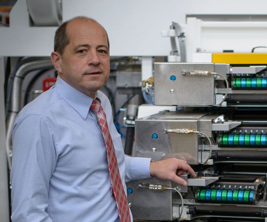 André Brülhart vor einer Hochleistungsdruckmaschine mit Farbmesser - einevon Swissmeca hergestellte Baugruppe. André Brülhart vor einer Hochleistungsdruckmaschine mit Farbmesser - einevon Swissmeca hergestellte Baugruppe.