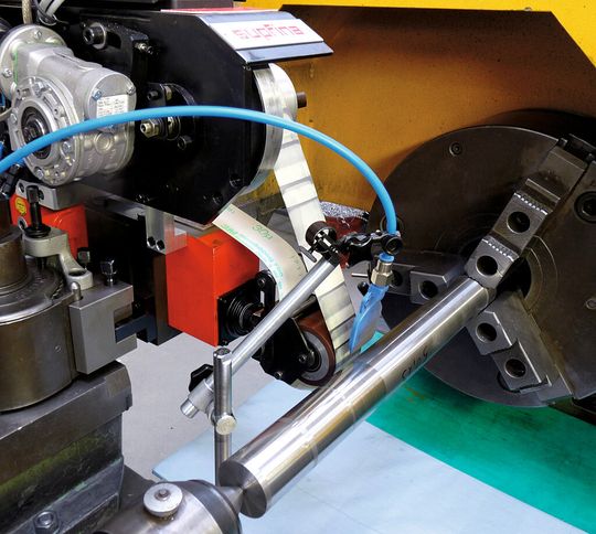 Der Versuchsaufbau an einem MAG-Boehringer-Drehautomaten besteht aus einem Mikrofinishing-Aufsatz mit Schleifband aus Aluminiumoxid, das mittels Druckluft und Gummi-Andrückrolle im Eingriff gehalten wird. Der Versuchsaufbau an einem MAG-Boehringer-Drehautomaten besteht aus einem Mikrofinishing-Aufsatz mit Schleifband aus Aluminiumoxid, das mittels Druckluft und Gummi-Andrückrolle im Eingriff gehalten wird.