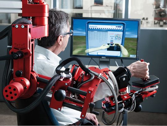 Nach einem Schlaganfall müssen alltägliche Bewegungen neu eintrainiert werden: Therapieroboter ARMin unterstützt den behinderten Arm des Patienten bei der Aufgabe, die der Bildschirm als virtuelle Realität vorgibt.