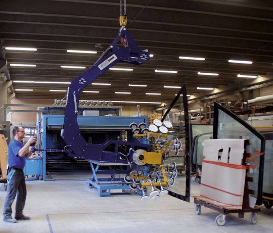 Eine Frontscheibe wird mittels Vakuumheber zum Transportwagen gebracht. Die nicht benötigten Saugteller sind abgeschaltet und die Arme nach aussen weggekippt. Eine Frontscheibe wird mittels Vakuumheber zum Transportwagen gebracht. Die nicht benötigten Saugteller sind abgeschaltet und die Arme nach aussen weggekippt.