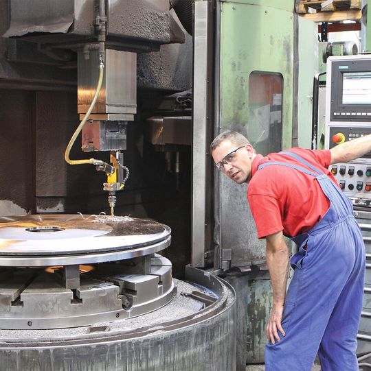 Bild 1: Anstatt die bis zu 40 mm dicken Hauptringe auf einer separaten Anlage mit Aufspannbohrungen zu versehen, geschieht das jetzt direkt an der Karusselldrehbank mit einer Druckluft-Bohrmaschine. Bild 1: Anstatt die bis zu 40 mm dicken Hauptringe auf einer separaten Anlage mit Aufspannbohrungen zu versehen, geschieht das jetzt direkt an der Karusselldrehbank mit einer Druckluft-Bohrmaschine.