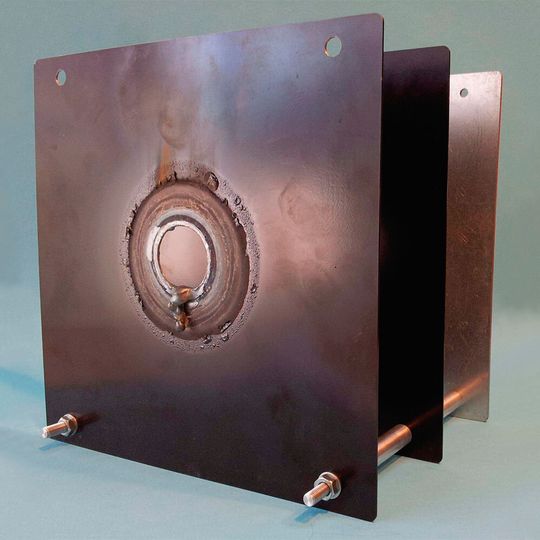Bild 1: Probe einer Laserschutzwand aus drei Stahlplatten in den Dicken 1,5 mm, 1,5 mm und 3 mm im Abstand von jeweils 100 mm. Die beiden ersten Platten sind geschwärzt. Bei einer Bestrahlung mit 5 kW auf einer kreisrunden Fläche mit dem Durchmesser 90 mm betrug die Standzeit lediglich etwa 30 s. Bild 1: Probe einer Laserschutzwand aus drei Stahlplatten in den Dicken 1,5 mm, 1,5 mm und 3 mm im Abstand von jeweils 100 mm. Die beiden ersten Platten sind geschwärzt. Bei einer Bestrahlung mit 5 kW auf einer kreisrunden Fläche mit dem Durchmesser 90 mm betrug die Standzeit lediglich etwa 30 s.
