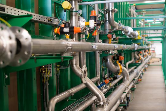 Rohrleitungssysteme verbinden die Fermentercontainer mit der Technikzentrale. Der Rohrgang wird vor der Inbetriebnahme noch baulich geschlossen. Rohrleitungssysteme verbinden die Fermentercontainer mit der Technikzentrale. Der Rohrgang wird vor der Inbetriebnahme noch baulich geschlossen.