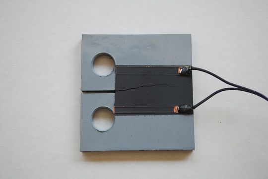 Figure1: Eprouvette CT (compact tension) avec une couche graphite pour mesurer la propagation de la fissure sous charge dynamique. Figure1: Eprouvette CT (compact tension) avec une couche graphite pour mesurer la propagation de la fissure sous charge dynamique.