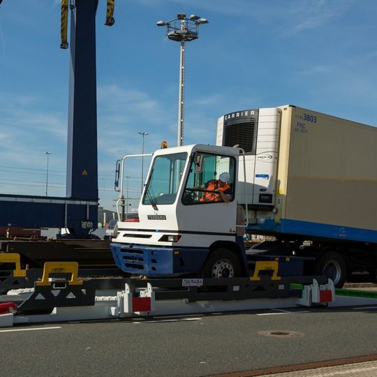 Das Nikrasa-System besteht aus zwei Teilen: der Terminal-Plattform (weiß) und der Transport-Plattform (schwarz). Die Terminalzugmaschine positioniert den Trailer mittig auf der Transport-Plattform. Das Nikrasa-System besteht aus zwei Teilen: der Terminal-Plattform (weiß) und der Transport-Plattform (schwarz). Die Terminalzugmaschine positioniert den Trailer mittig auf der Transport-Plattform.