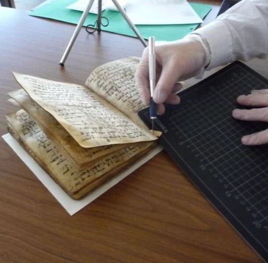 Ein Experte entnimmt der Koranhandschrift eine Probe für die Datierung. Foto: Dr. Wilfried Lagler/Universitätsbibliothek Tübingen. Ein Experte entnimmt der Koranhandschrift eine Probe für die Datierung. Foto: Dr. Wilfried Lagler/Universitätsbibliothek Tübingen.