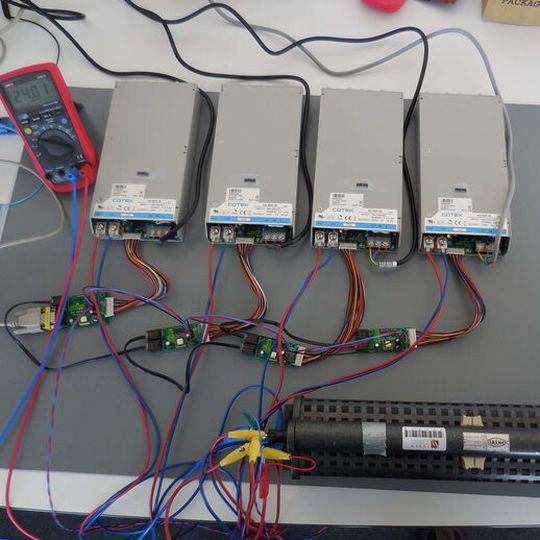 Bild 1: Aufbau eines Parallelbetriebs von vier Netzteilen mit Modell CT-251 und drei Modellen CT-551 im Labor. Damit die Funktion des „current sharings“, der Stromaufteilung unter den einzelnen Geräten, gewährleistet ist, muss noch eine Verbindung zwischen den einzelnen Netzteilen über Schnittstellenplatinen hergestellt werden. Die Schnittstellenplatinen haben hierfür einen Steckverbinder, an welchem man die entsprechende Verdrahtung vornehmen kann. Bild 1: Aufbau eines Parallelbetriebs von vier Netzteilen mit Modell CT-251 und drei Modellen CT-551 im Labor. Damit die Funktion des „current sharings“, der Stromaufteilung unter den einzelnen Geräten, gewährleistet ist, muss noch eine Verbindung zwischen den einzelnen Netzteilen über Schnittstellenplatinen hergestellt werden. Die Schnittstellenplatinen haben hierfür einen Steckverbinder, an welchem man die entsprechende Verdrahtung vornehmen kann.